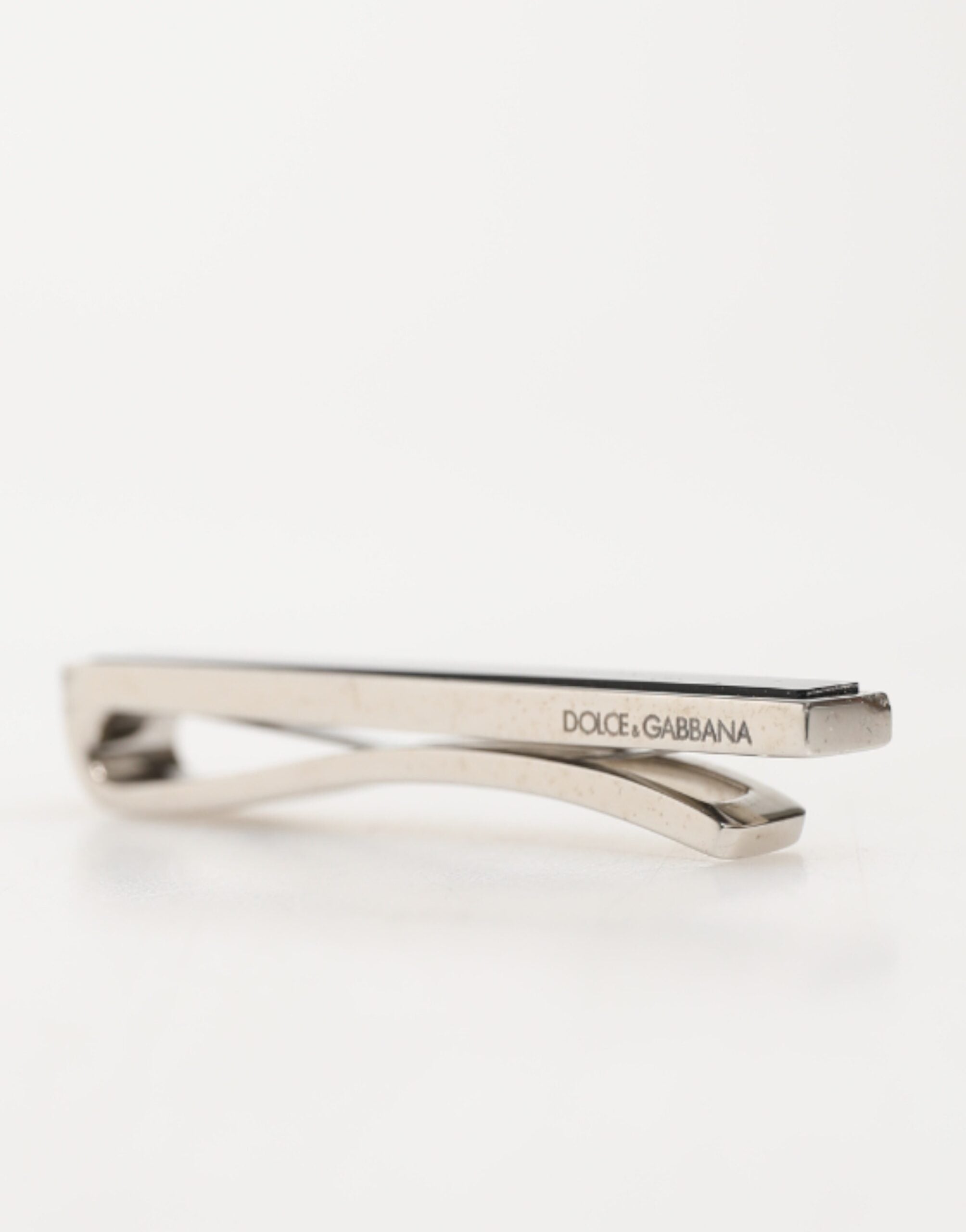 Close‑up detail of Dolce & Gabbana silver logo engraved tie clip by KILAUE
